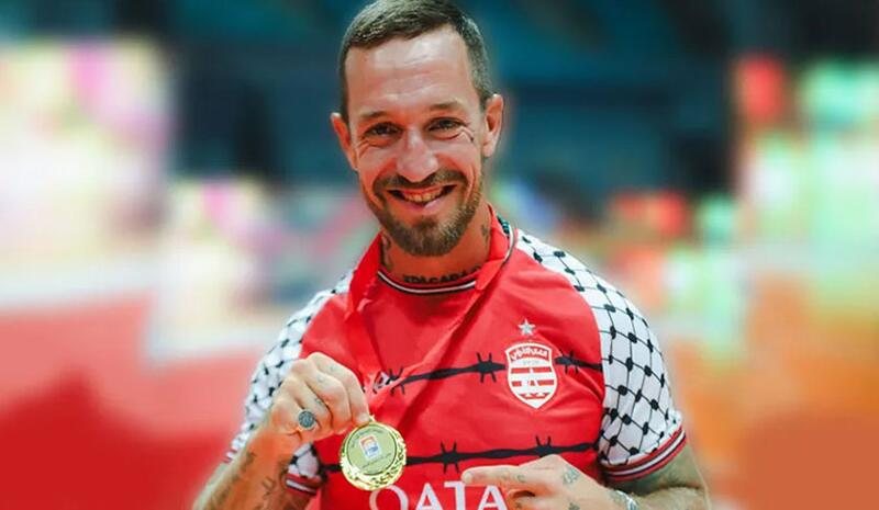 Fergie Chambers con la camiseta del Club Africain y una kufiya, sosteniendo una medalla.